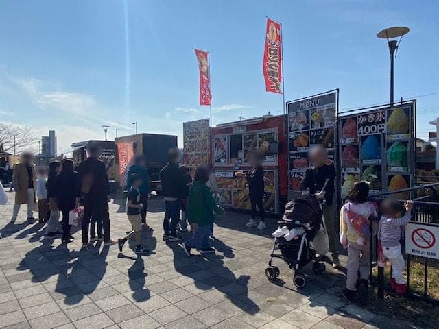屋外のイベント。キッチンカーの前にお客さんが並んでいる